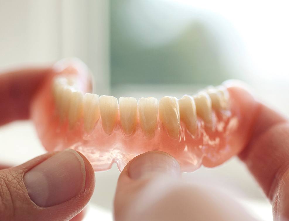 Close-up of hands holding dentures in Abingdon, VA