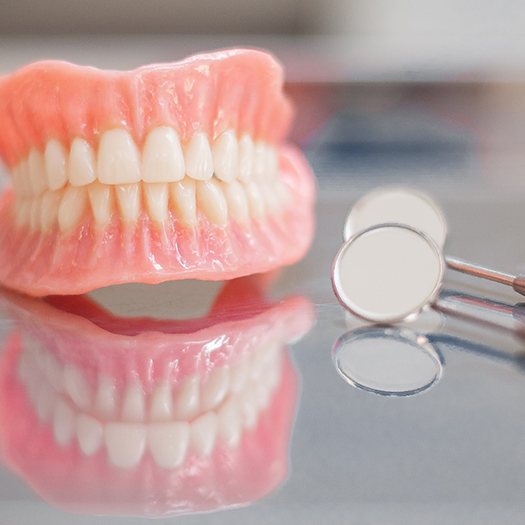 Dentures in Abingdon, VA and dental mirror on a reflective table