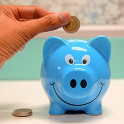 Hand putting coin in a piggy bank