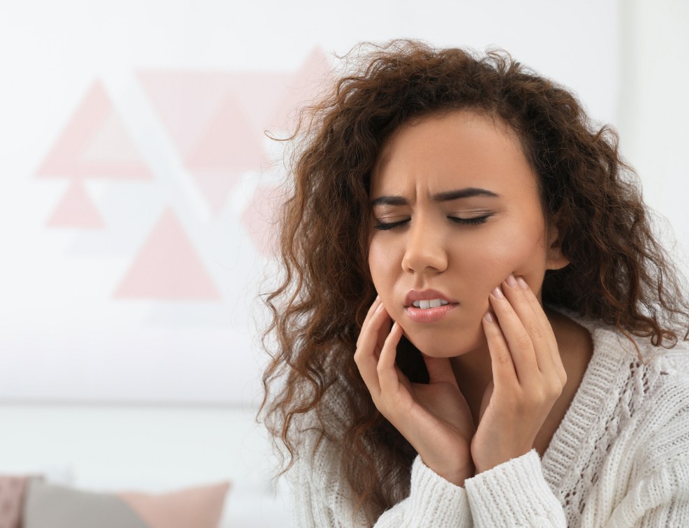 Woman in need of emergency dentistry holding her jaw