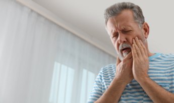 Man with lost dental crown holding cheek