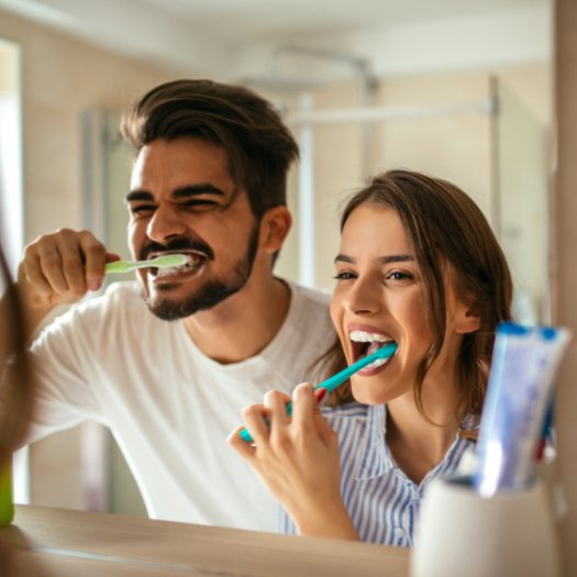 Man and woman brushing teeth to prevent dental emergencies