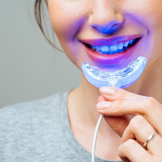 Woman using LED light to whiten her teeth