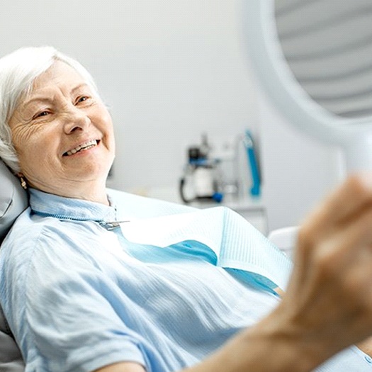 elderly dental patient admiring her new smile in a mirror