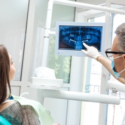 implant dentist showing his patient their dental X-rays
