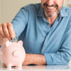 man putting coins into a pink piggy bank