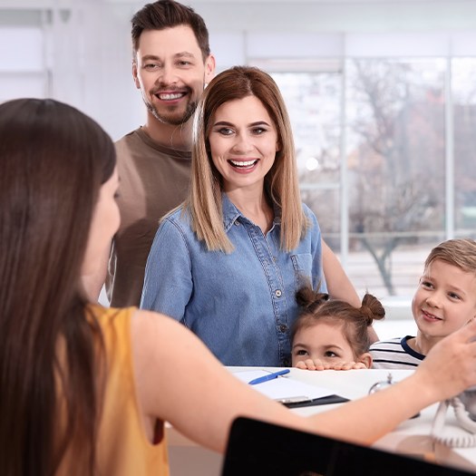 Family of four checking in at dental office reception desk