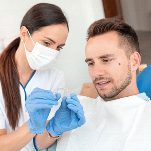 A dentist shows a male patient how Invisalign will work to fix his smile