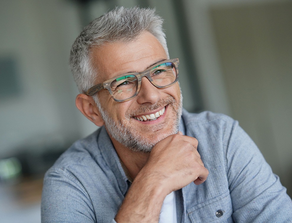 Older man smiling after replacing missing teeth