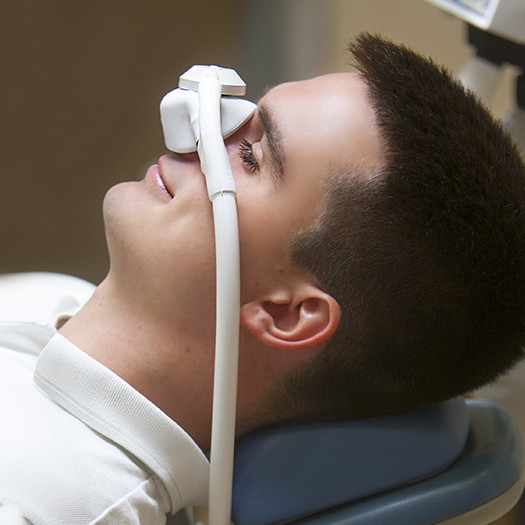 Man with nitrous oxide dental sedation nose mask relaxing during treatment