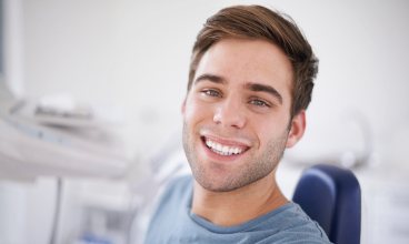 Man in dental chair smiling after preventive dentistry visit