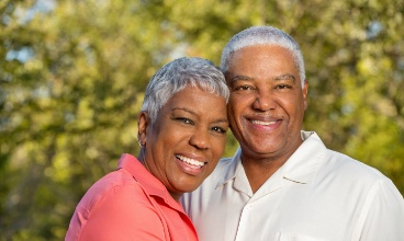 Older man and woman smiling after restorative dentistry