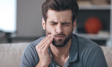 Man in need of emergency dentistry holding his jaw