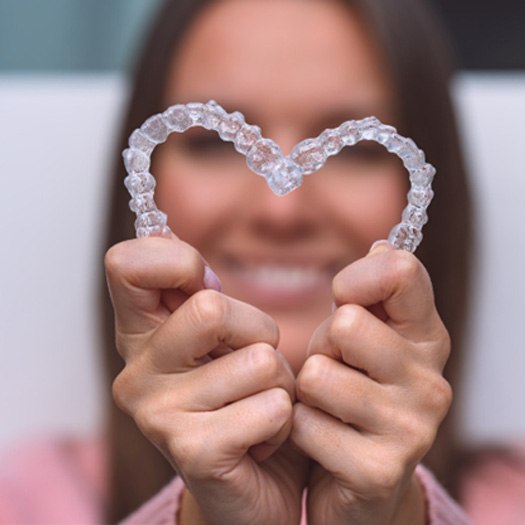 Woman holding two SureSmile aligners in heart shape