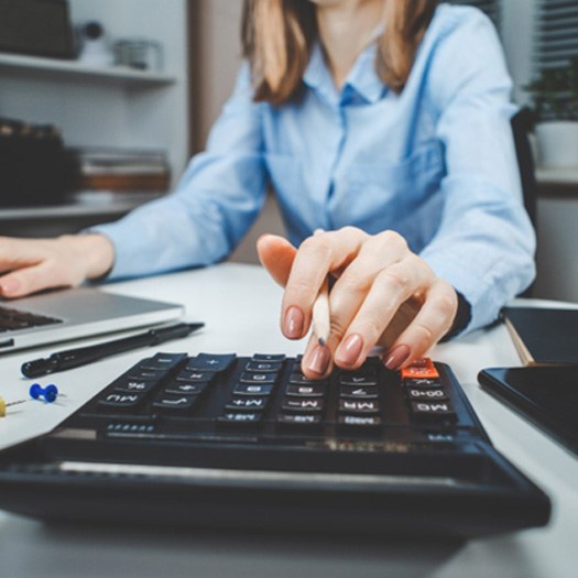 Woman using calculator, budgeting for dental treatment