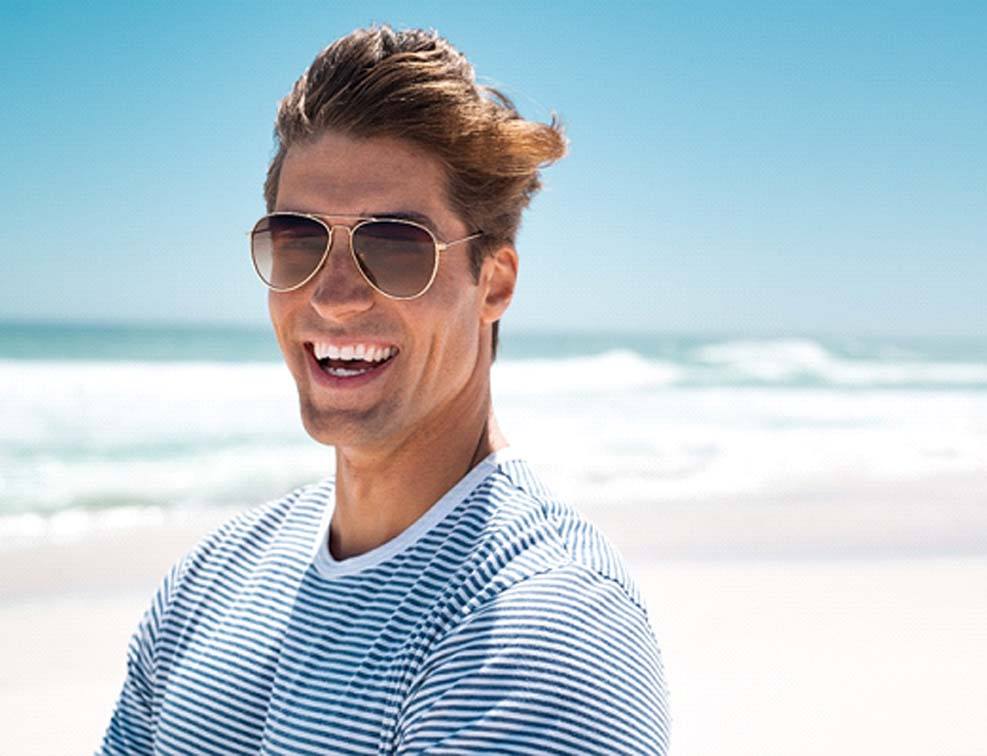Man with sunglasses on beach smiling with veneers in Abingdon, VA