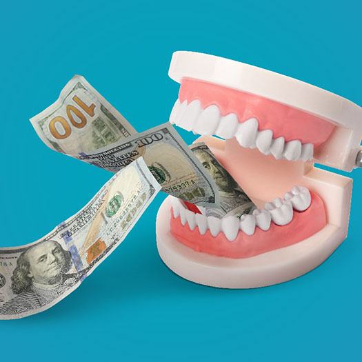 A model jaw biting money, symbolizing the cost of veneers in Abingdon