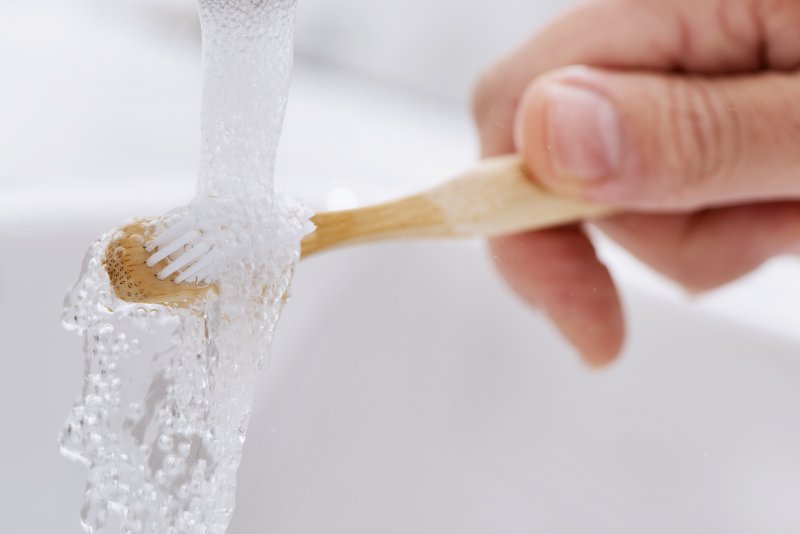 person rinsing their toothbrush with running water
