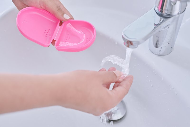 a person cleaning their clear aligners in Abingdon