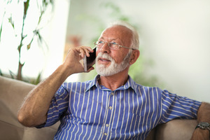Senior man sitting on couch talking on phone